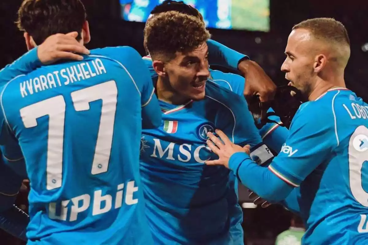 Muchos hombres vestidos con la camiseta azul del Napoli abrazados celebrando un gol