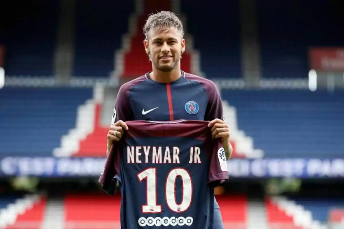 A soccer player holding a jersey with the number 10 in a stadium. A soccer player holding a jersey with the number 10 in a stadium.