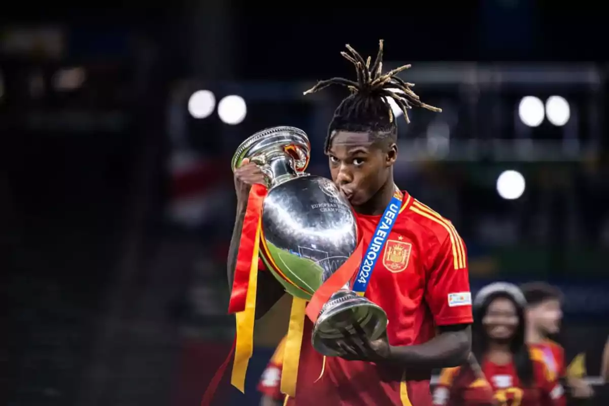 Jugador de fútbol con la camiseta de España besando un trofeo de la UEFA Euro 2020.