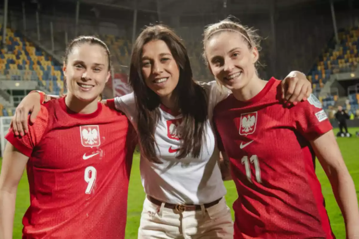 Se pueden ver a tres personas, dos de ellas vestidas con la equipacion de la selección de Polonia, una de ellas es Pajor. En el medio una mujer vestida con ropa de calle