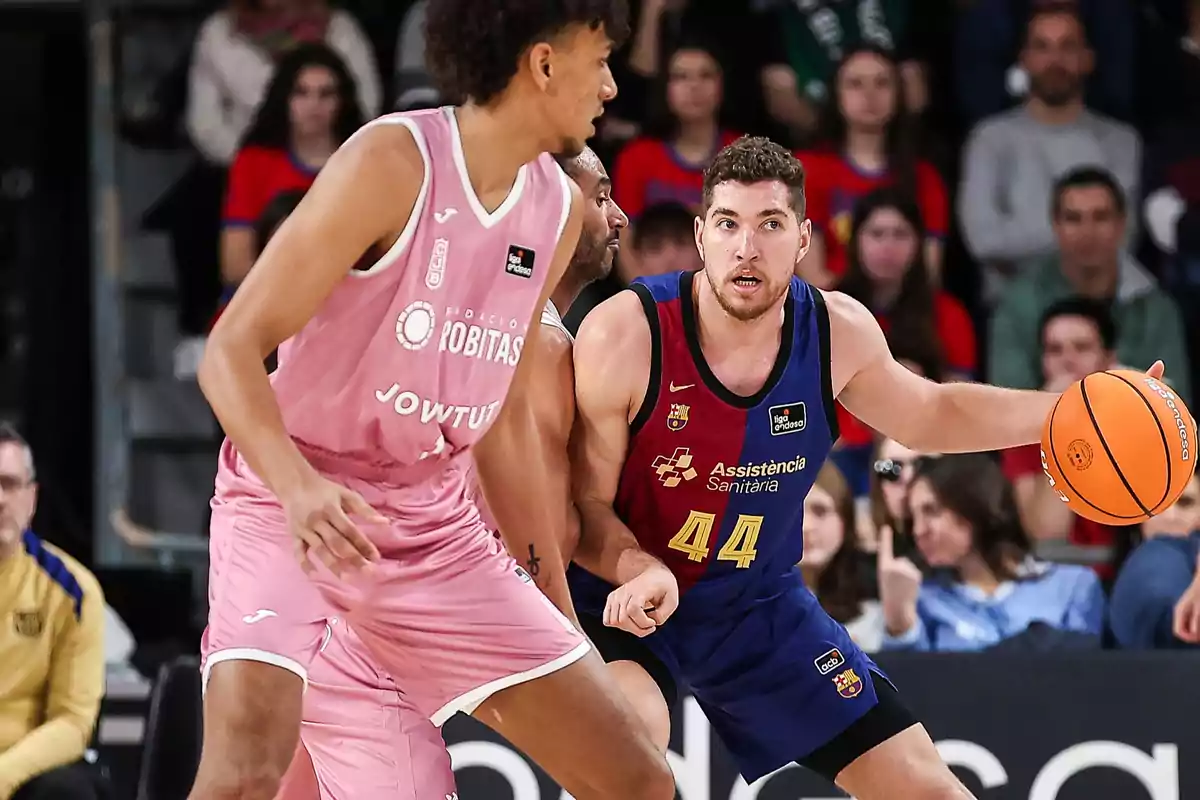 Two basketball players in action during a game, one in a pink uniform and the other in a blue and red uniform, while the player with the ball tries to advance.