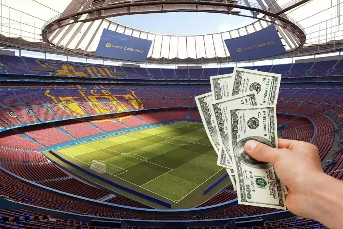 Una mano sosteniendo billetes de dólar frente a un estadio de fútbol vacío.