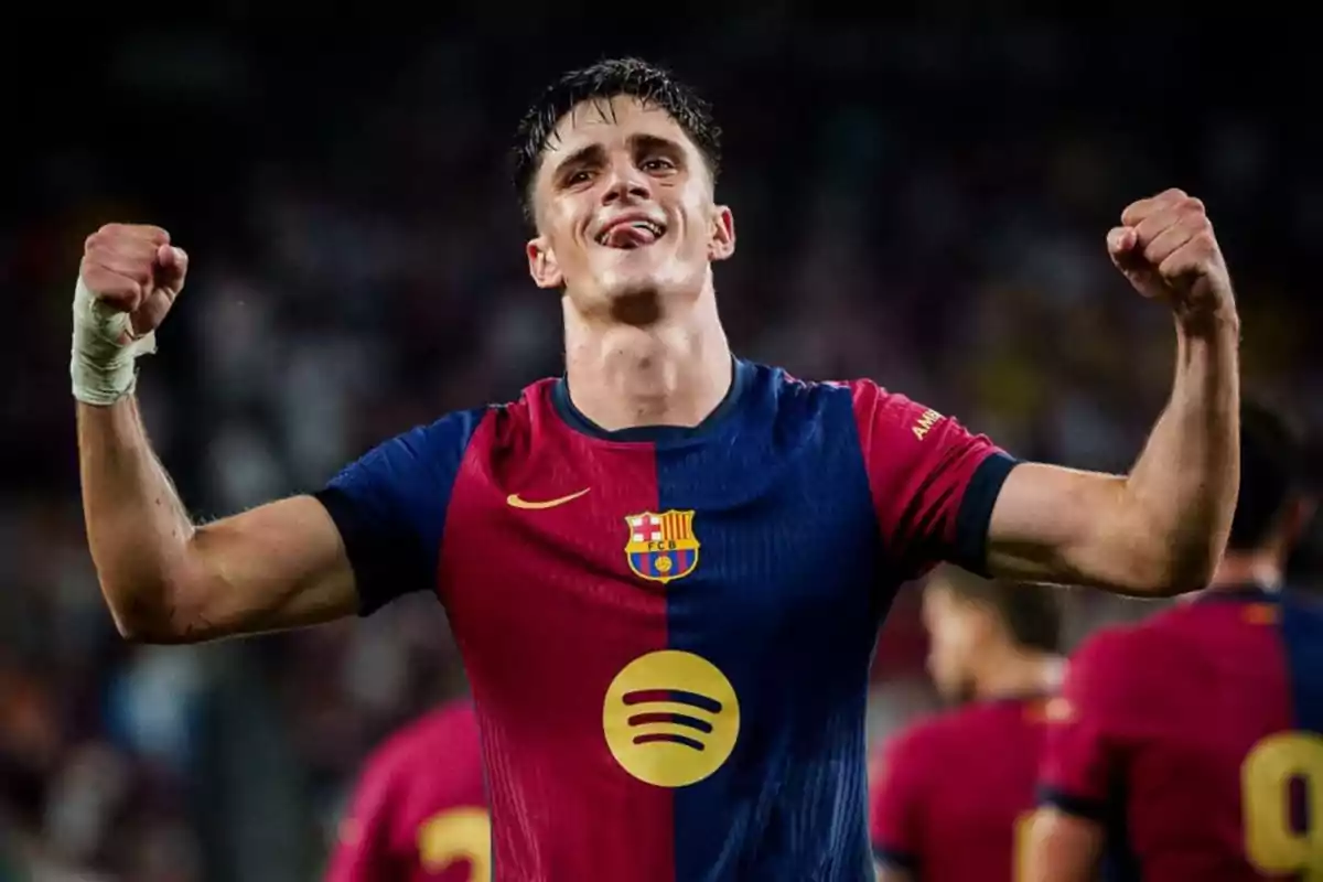 Soccer player celebrating with his arms raised while wearing the FC Barcelona shirt.