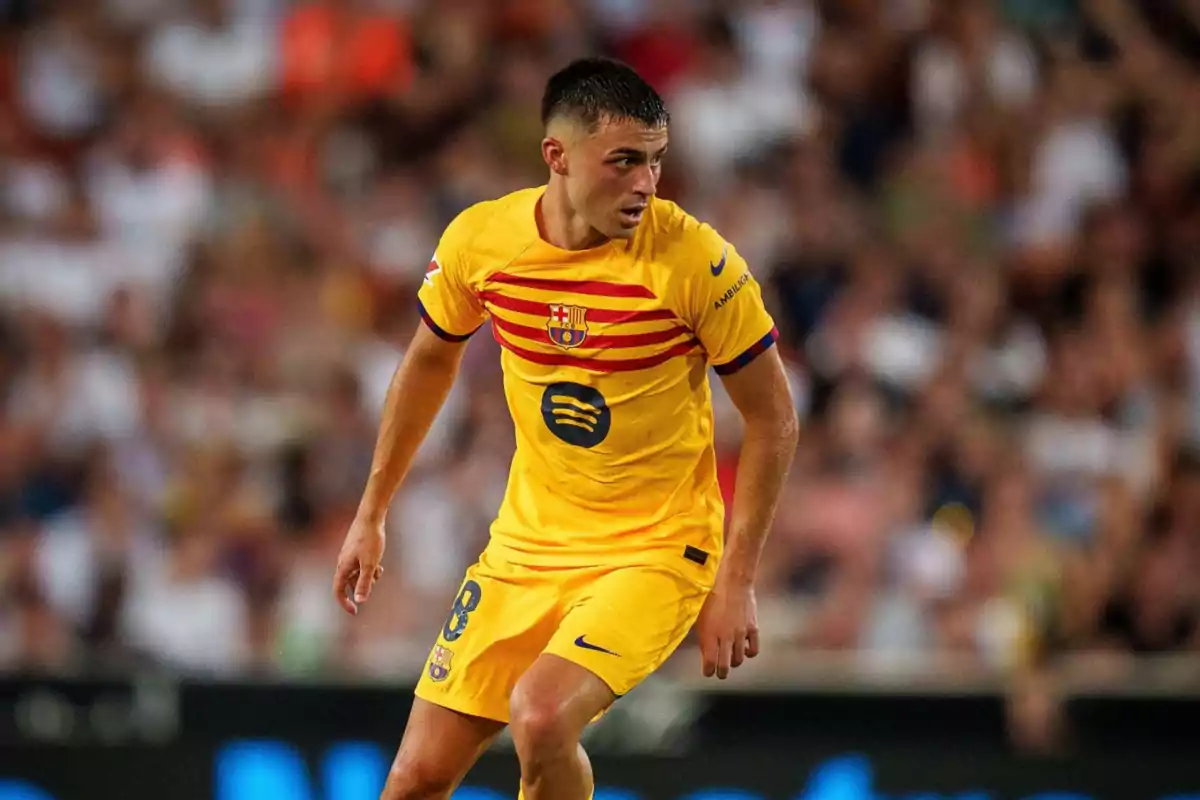 Jugador de fútbol con uniforme amarillo del FC Barcelona en el campo de juego.