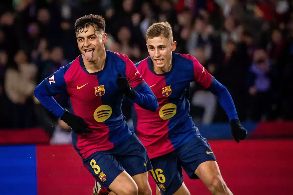 Two FC Barcelona soccer players celebrate a goal on the field.