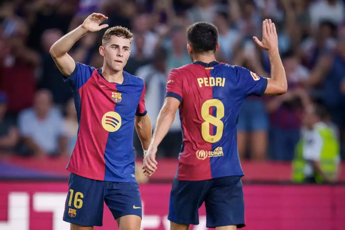 Dos jugadores del FC Barcelona celebrando en el campo de fútbol.