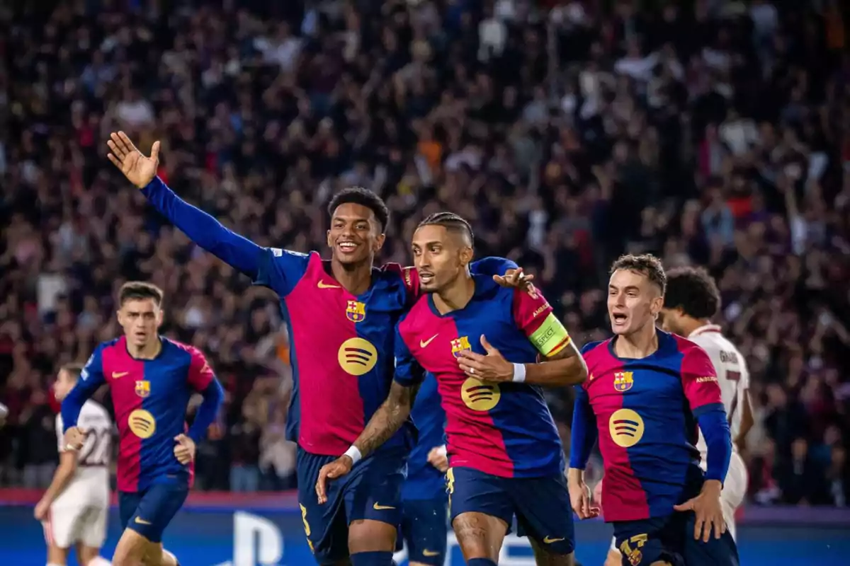 Jugadores del FC Barcelona celebrando un gol en un partido de fútbol con el público de fondo.