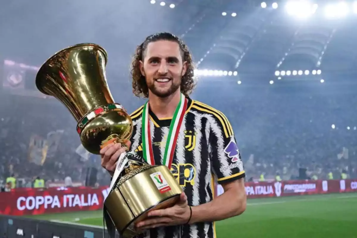 Jugador de fútbol sosteniendo un trofeo en un estadio después de ganar la Coppa Italia.