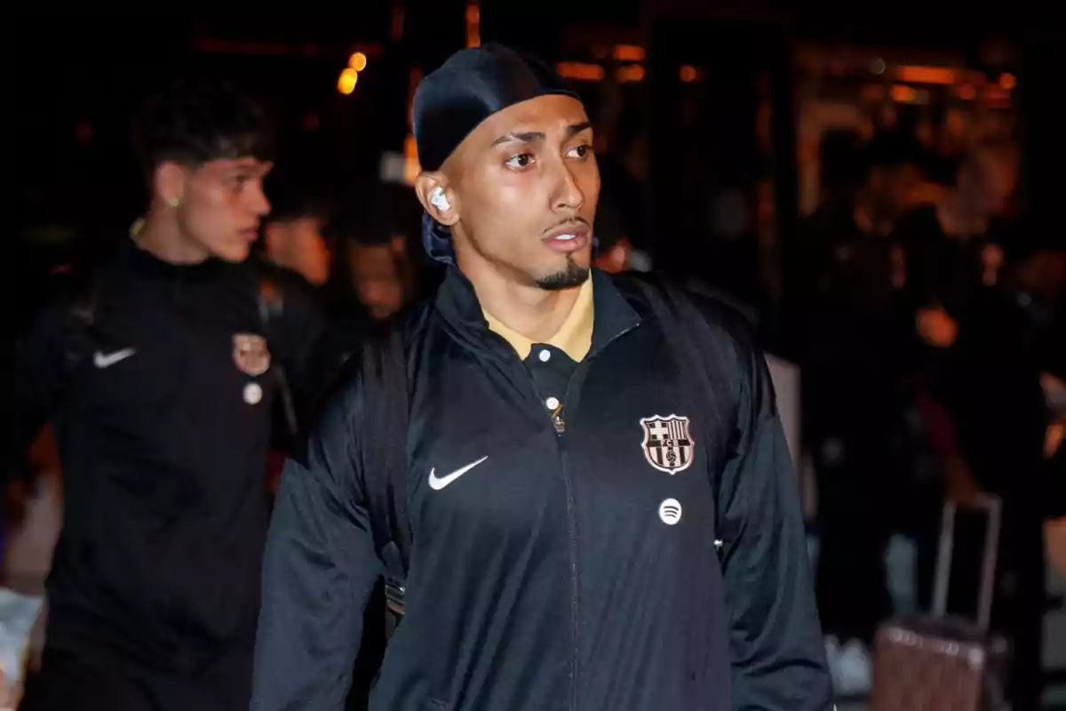 A soccer player in a FC Barcelona uniform walks in a dark environment.