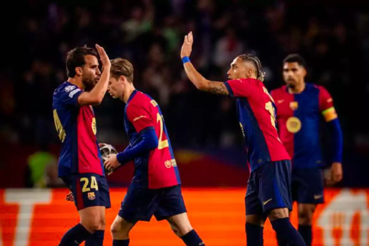 Jugadores de fútbol con uniforme azul y rojo celebran en el campo durante un partido. Jugadores de fútbol con uniforme azul y rojo celebran en el campo durante un partido.