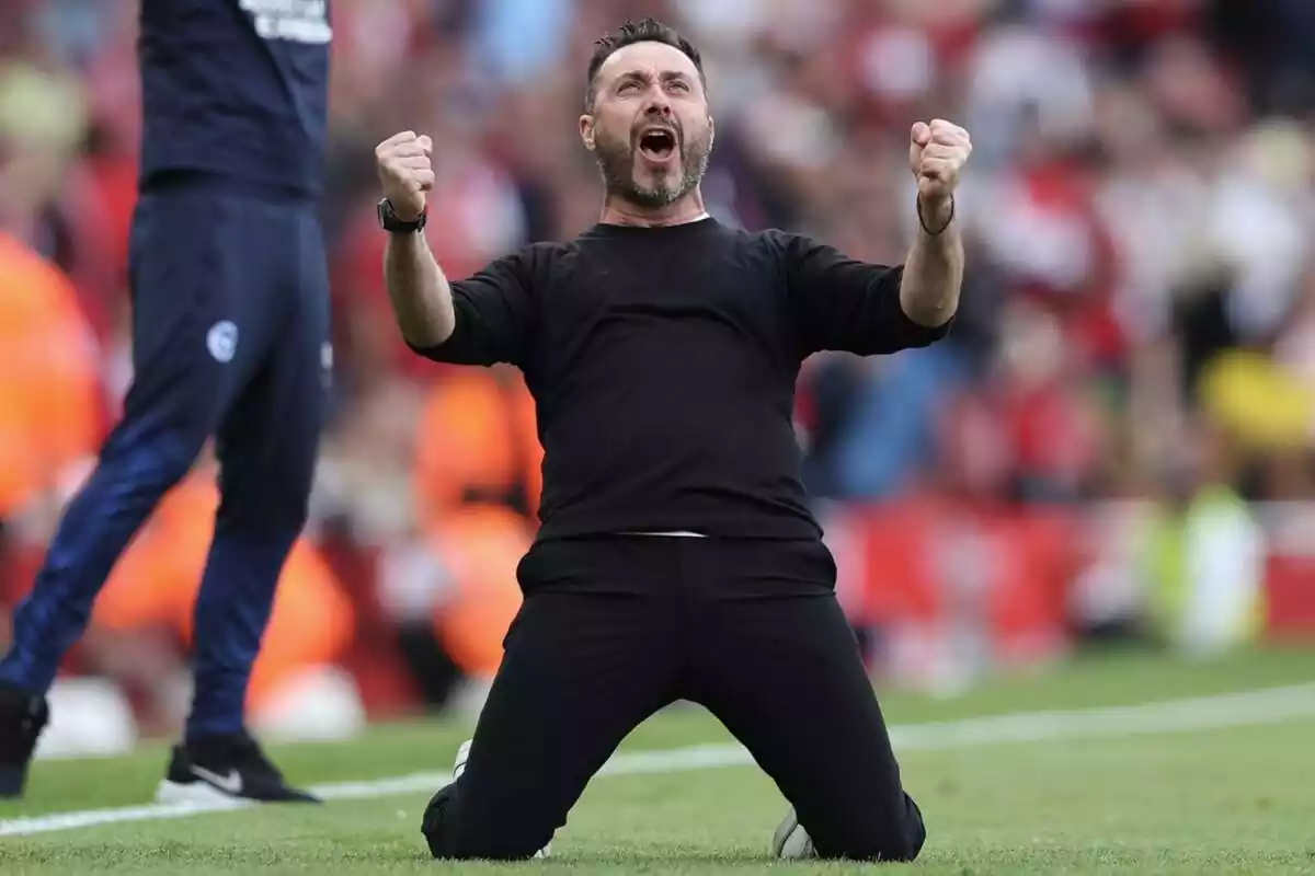 Roberto De Zerbi, de rodillas sobre un campo de fútbol gritando un gol con euforia