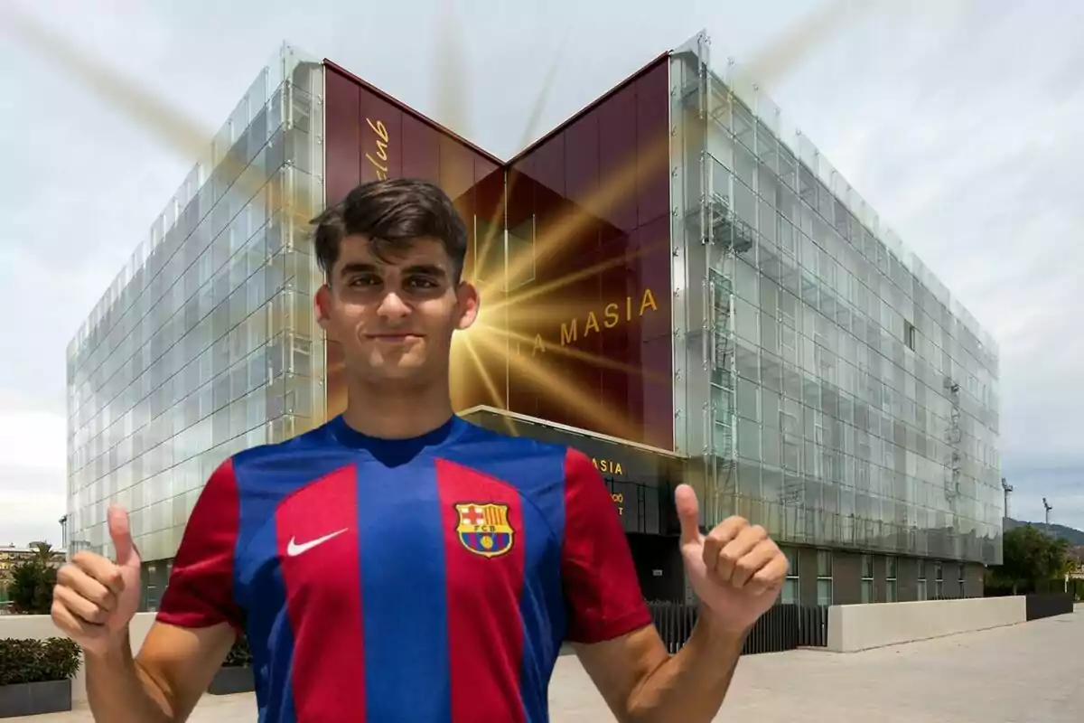 Un joven con la camiseta del FC Barcelona posando frente al edificio de La Masia.