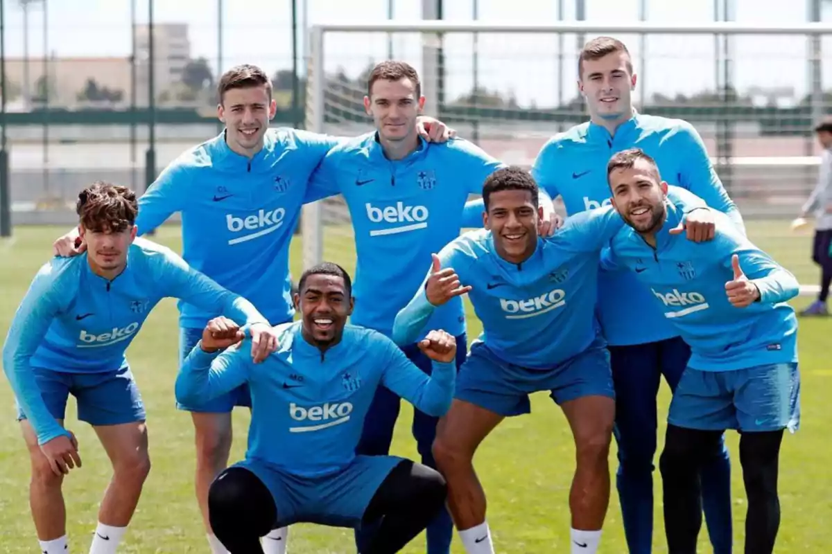 Un grupo de jugadores de fútbol posando juntos en el campo de entrenamiento, todos llevan uniformes de entrenamiento azules con el logo de "beko".