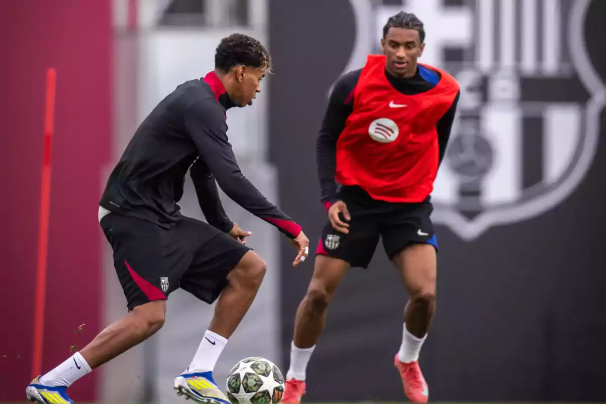 Dos jugadores de fútbol entrenando en un campo con uno de ellos controlando el balón mientras el otro observa. Dos jugadores de fútbol entrenando en un campo con uno de ellos controlando el balón mientras el otro observa.